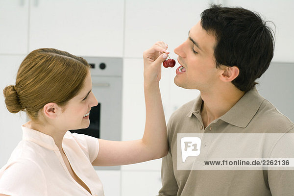Woman feeding man cherries  side view