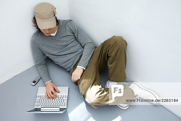 Junger Mann auf dem Boden sitzend  mit Laptop-Computer  hoher Blickwinkel