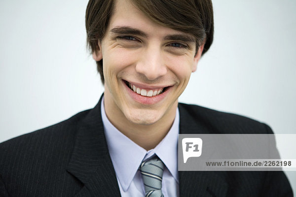 Junger Mann im Anzug lächelnd vor der Kamera  Portrait  Nahaufnahme