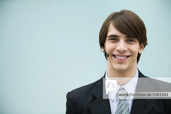 Young man in suit using headset  smiling at camera  portrait
