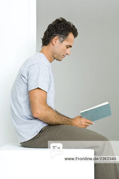 Man sitting  reading book  side view