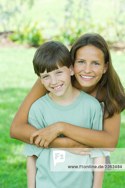 Teenage girl and younger brother smiling at camera together  portrait