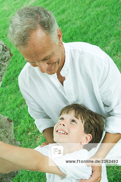 Grandfather and grandson outdoors together  smiling at each other  tilted high angle view