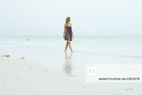 Frau im Sonnenkleid am Strand entlang,  Blick auf die Aussicht