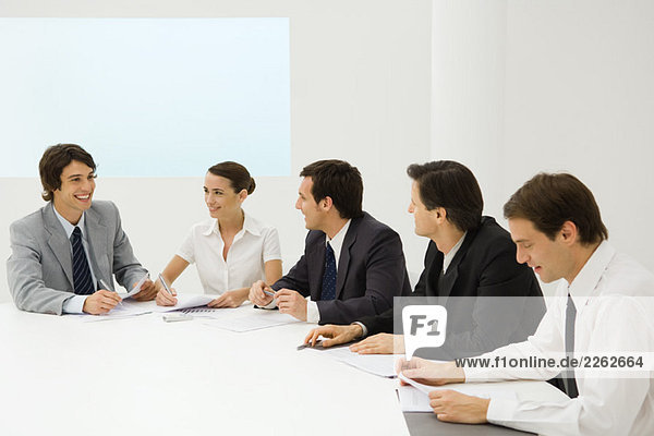 Group of business associates sitting together at conference table  smiling