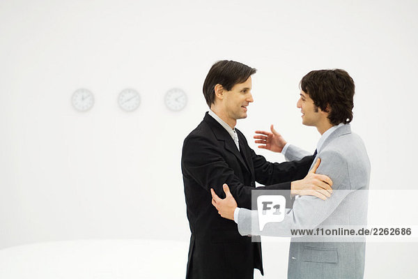Zwei männliche Geschäftspartner von Angesicht zu Angesicht  Hände auf den Schultern  lächelnd