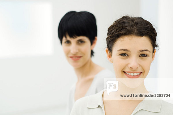 Zwei Geschäftsfrauen lächeln vor der Kamera  Fokus auf den Vordergrund  Porträt