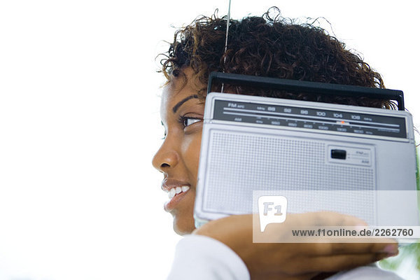Frau hält Radio am Ohr  lächelnd  Seitenansicht