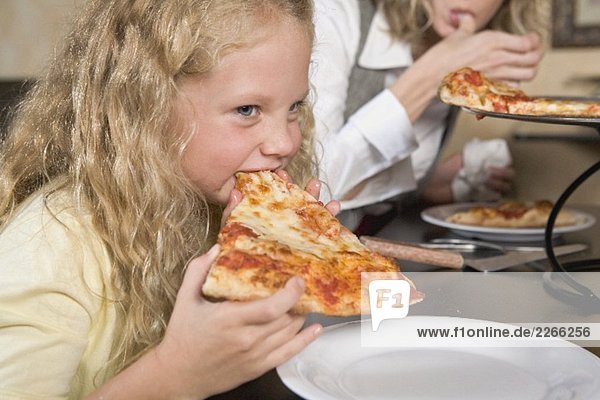 Blond girl eating a slice of pizza