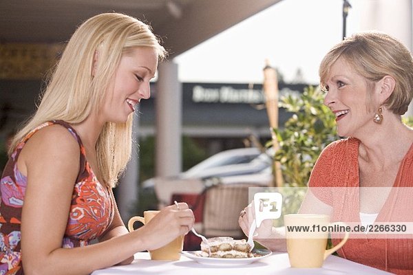Two women at street café sharing a piece of tiramisu