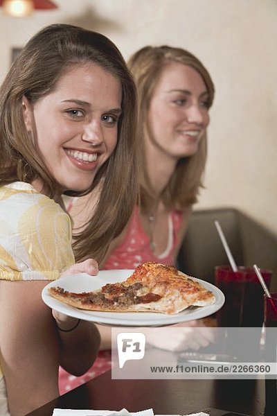 Two young women  one holding a plate of pizza