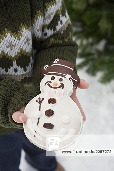 Child holding snowman biscuit