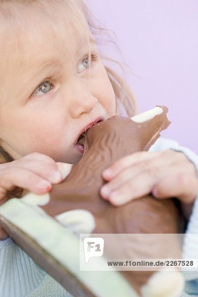 Kleines Mädchen isst Schokoladenosterhase
