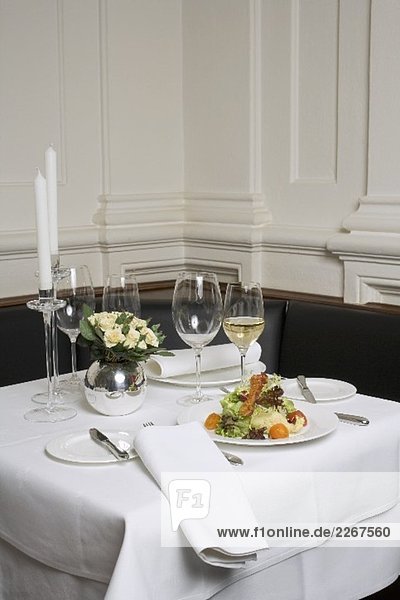 Gedeckter Tisch mit Salat und Weisswein im Restaurant