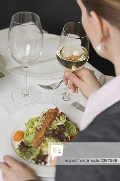 Frau trinkt Weisswein zum Salat im Restaurant