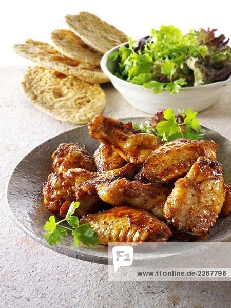 Gegrillte Hähnchenflügel mit Blattsalat und Brot