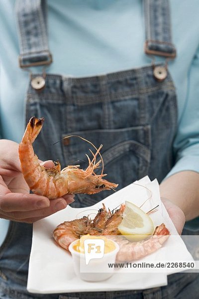 Woman holding tiger prawns with dip on napkin