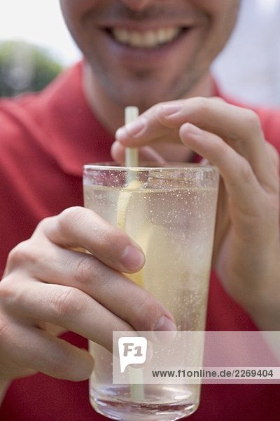 Mann hält Glas Zitronenlimonade mit Strohhalm