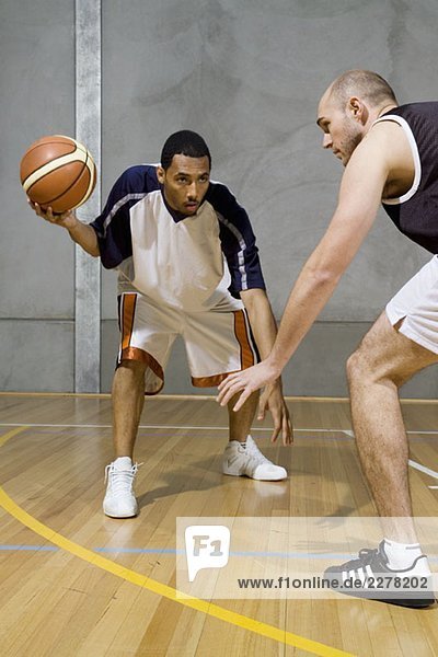 Ein Basketballspieler dribbelt den Ball und ein anderer Spieler bewacht ihn.