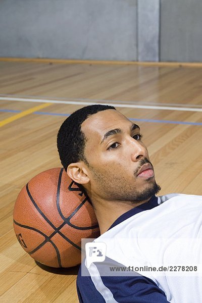 Ein junger Mann legt seinen Kopf auf einen Basketball.