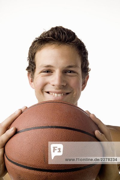Studioporträt eines jungen Mannes mit Basketball