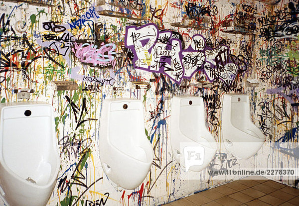 Urinale auf einer mit Graffiti bedeckten Wand