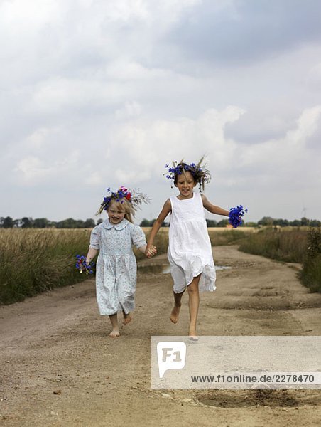 Zwei junge Mädchen  die eine Landstraße entlanglaufen.