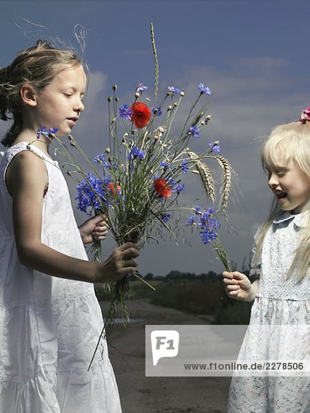 Zwei Mädchen mit Trauben auf Wildblumen