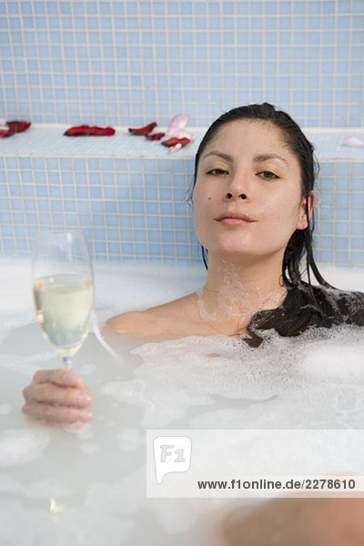 Eine Frau trinkt Champagner im Bad.