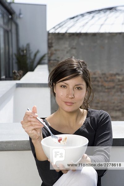 Eine Frau beim Frühstücken auf der Dachterrasse