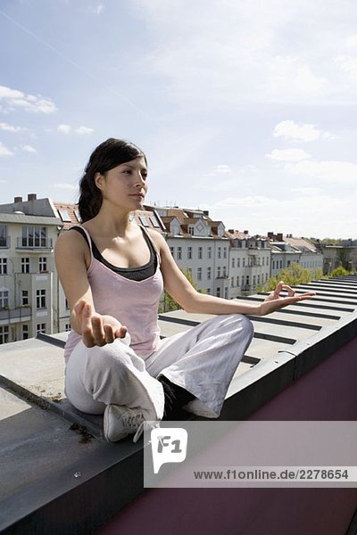 Eine junge Frau  die Yoga auf dem Dach praktiziert.