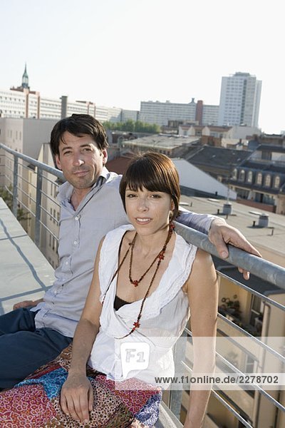 Ein Mann und eine Frau sitzen zusammen auf einer Dachterrasse.