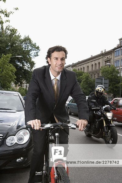 Ein Geschäftsmann  der auf einer Stadtstraße Fahrrad fährt.