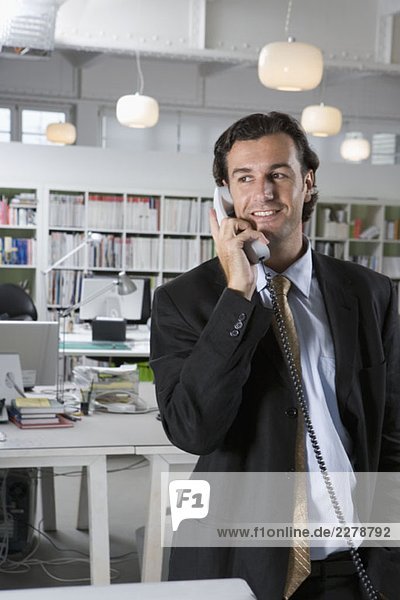 Ein Geschäftsmann  der ein Telefon in einem Büro benutzt.