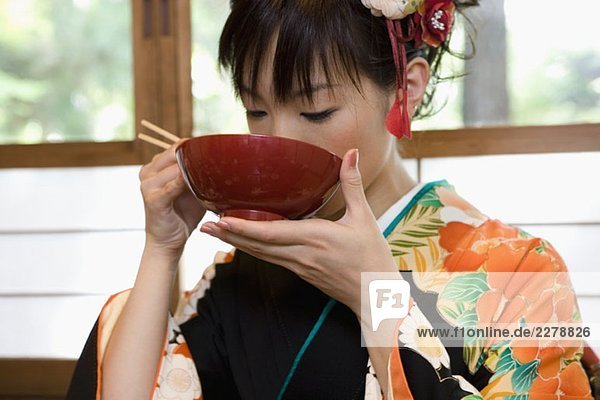 Eine Frau  die einen Kimono trägt und Suppe isst.