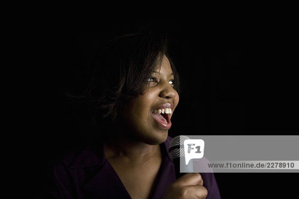 Eine Frau  die in ein Mikrofon singt.