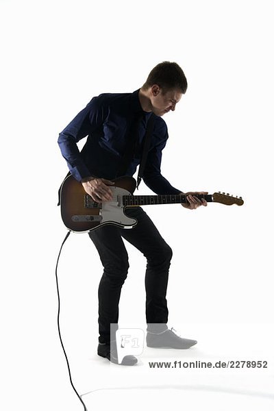 Studio shot of a man playing an electric guitar