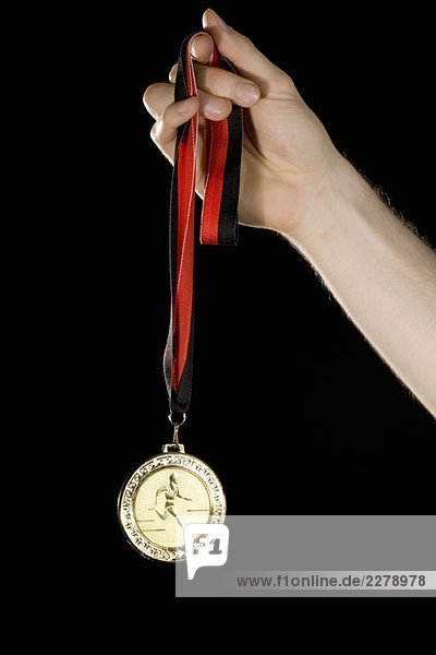 Eine Hand mit einer Goldmedaille