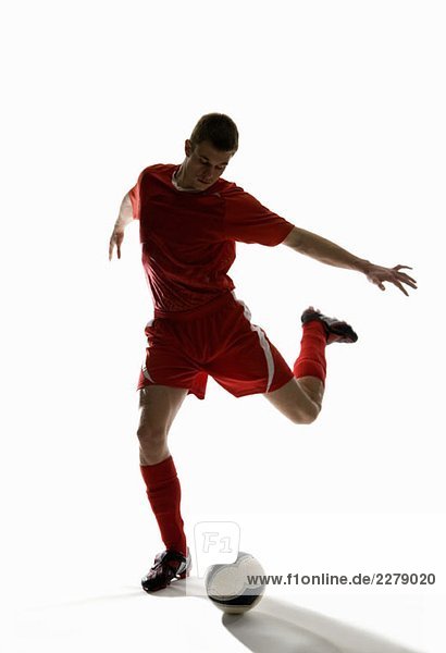 Studio shot of a soccer player kicking a soccer ball