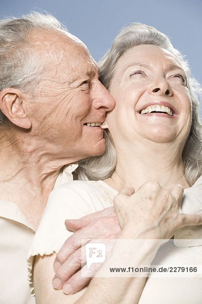 Ein älteres Paar  das sich umarmt und lacht.