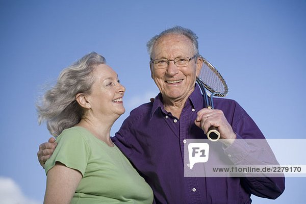 A senior couple with a tennis racket