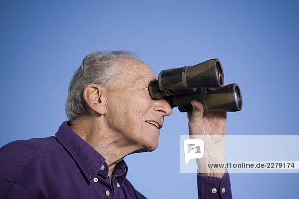 A senior man using binoculars