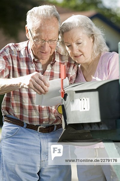 Ein älteres Ehepaar  das den Briefkasten überprüft.