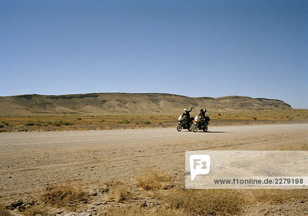 Zwei Motorradfahrer winken