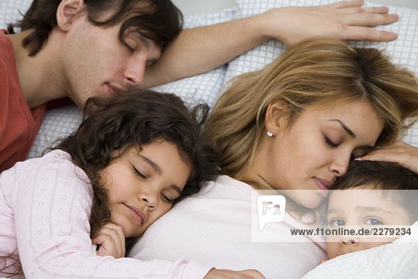 A family with two children sleeping in bed
