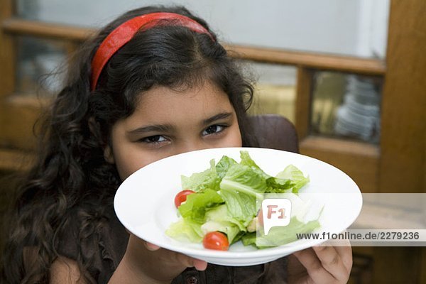 Ein Mädchen hält eine Schüssel Salat.