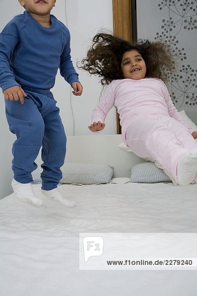 Zwei Kinder beim Springen auf einem Bett