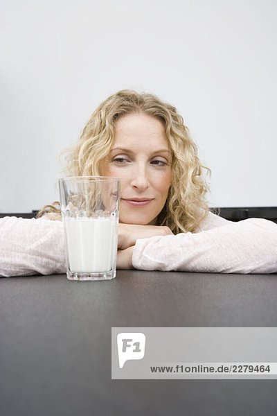 Eine Frau  die auf ein Glas Milch schaut.