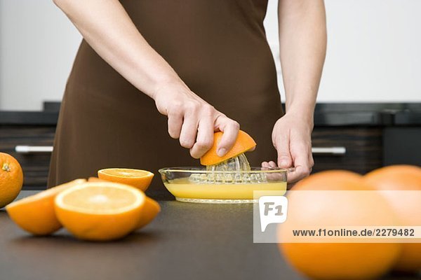 Eine Frau  die Orangen entsaftet.