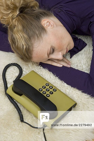 Eine Frau schläft neben einem Festnetztelefon.